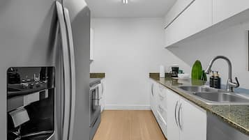 A modern kitchen with white cabinets, a stainless steel sink, and a built-in oven.