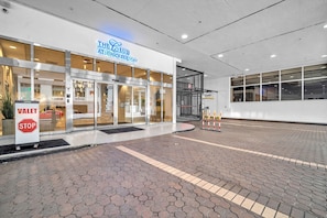 Entrada de hotel con señal de parada para valet, puerta de cristal y letrero que dice 'The Club at Brickell Way'.