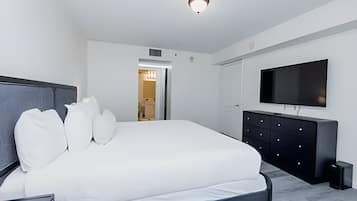 A modern bedroom with a large bed, a flat-screen TV, and a walk-in closet.