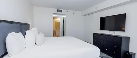 Ein modernes Schlafzimmer mit einem großen Bett, einem Flachbildfernseher und einem begehbaren Kleiderschrank.