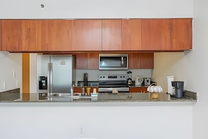 Una cocina moderna con armarios de madera, electrodomésticos de acero inoxidable y encimera de granito.