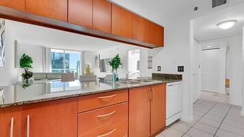 A modern kitchen with wooden cabinets, a granite countertop, and a view of the city.