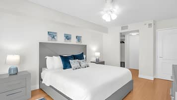 A modern bedroom with a large bed, bedside tables, a ceiling fan, and artwork on the wall.