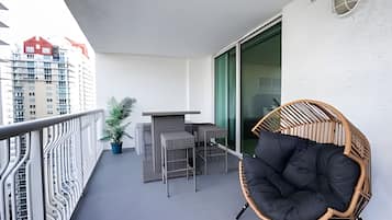 A balcony with a chair, a small table, and a potted plant.