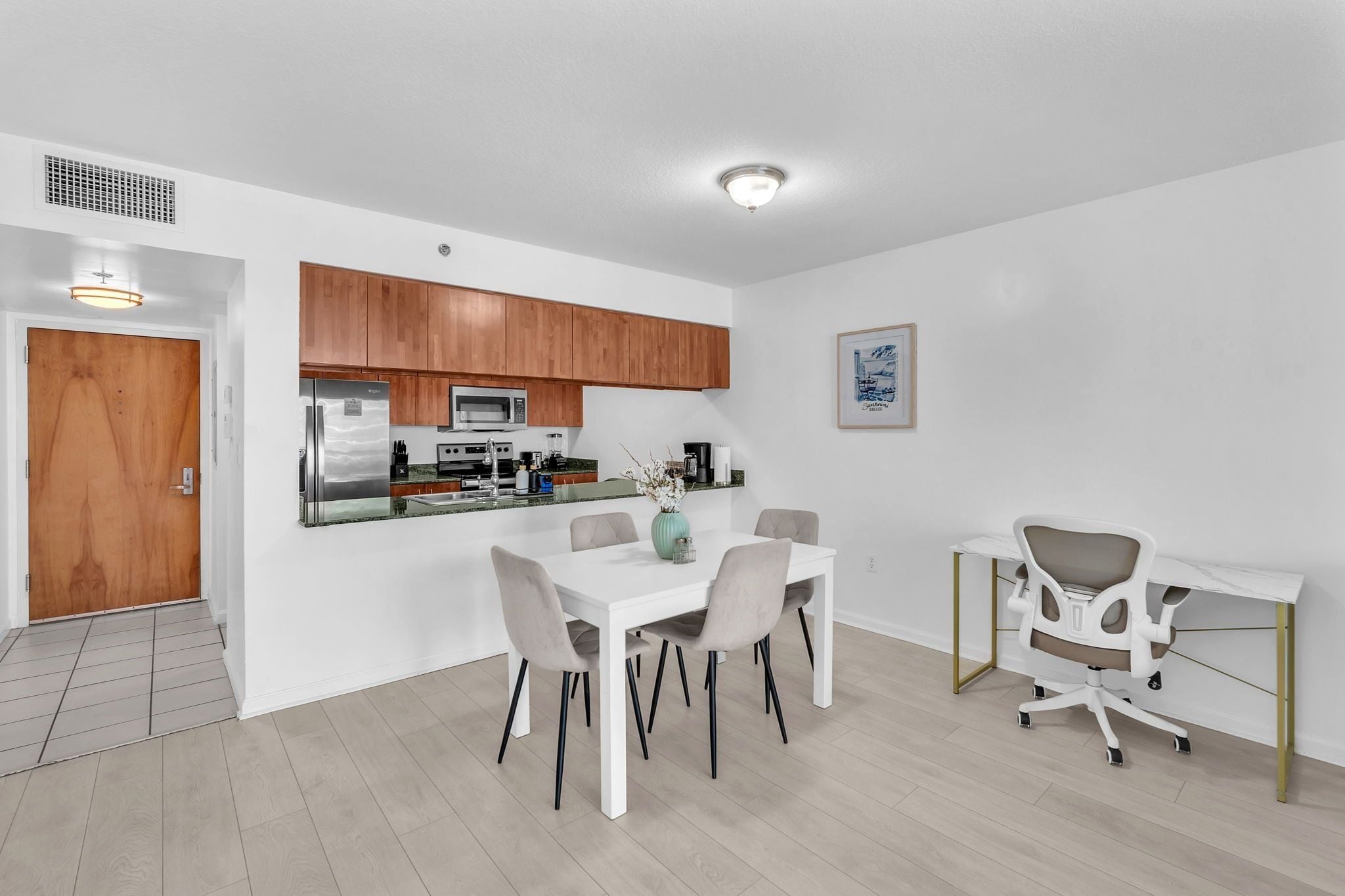 A modern kitchen with wooden cabinets, a built-in microwave, and a stainless steel refrigerator.
