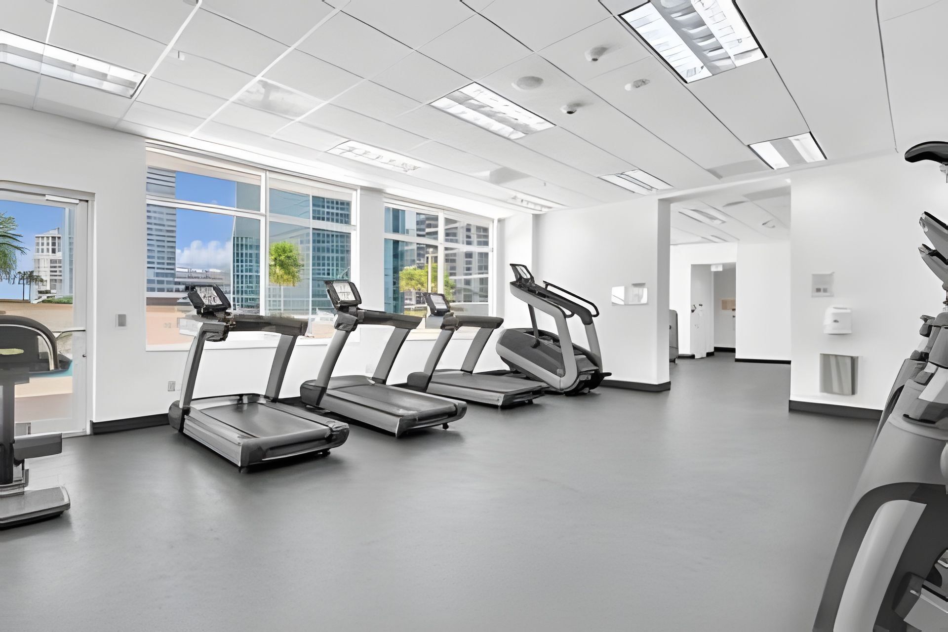 A gym with treadmills, a weight bench, and a wall-mounted exercise machine.