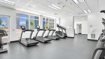 A gym with treadmills, a weight bench, and a wall-mounted exercise machine.