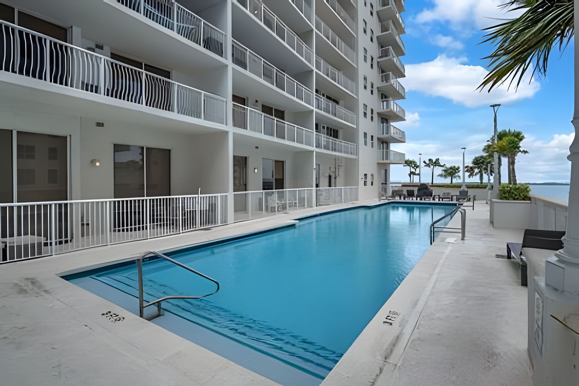 A hotel with a swimming pool, multiple balconies, and a view of the ocean.