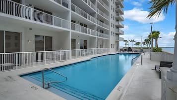 A hotel with a swimming pool, multiple balconies, and a view of the ocean.