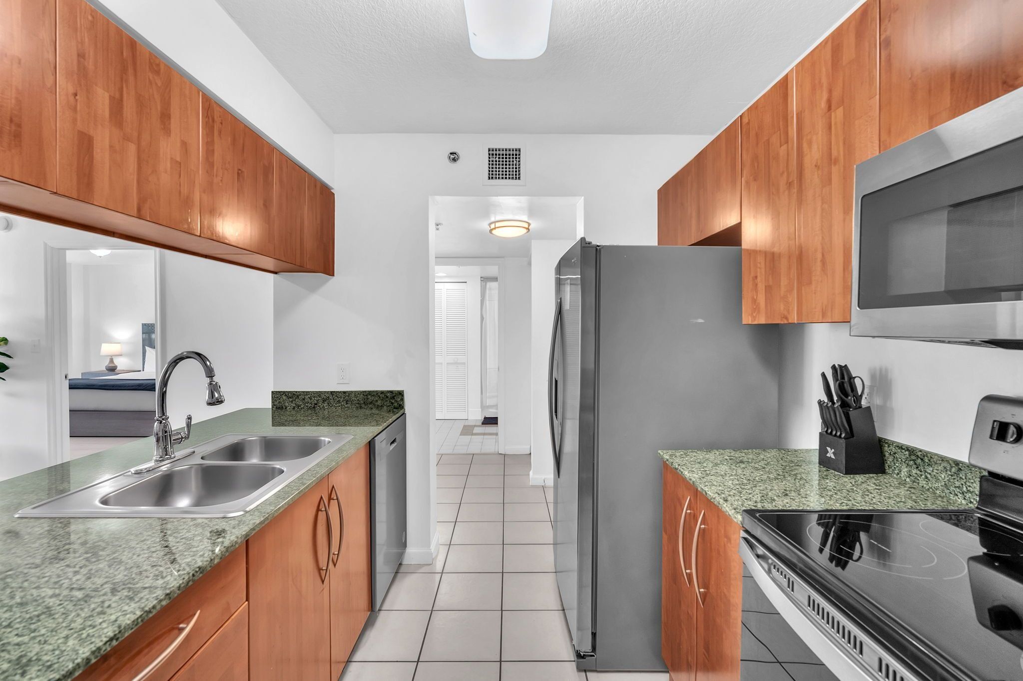 A modern kitchen with granite countertops, stainless steel appliances, and wooden cabinetry.