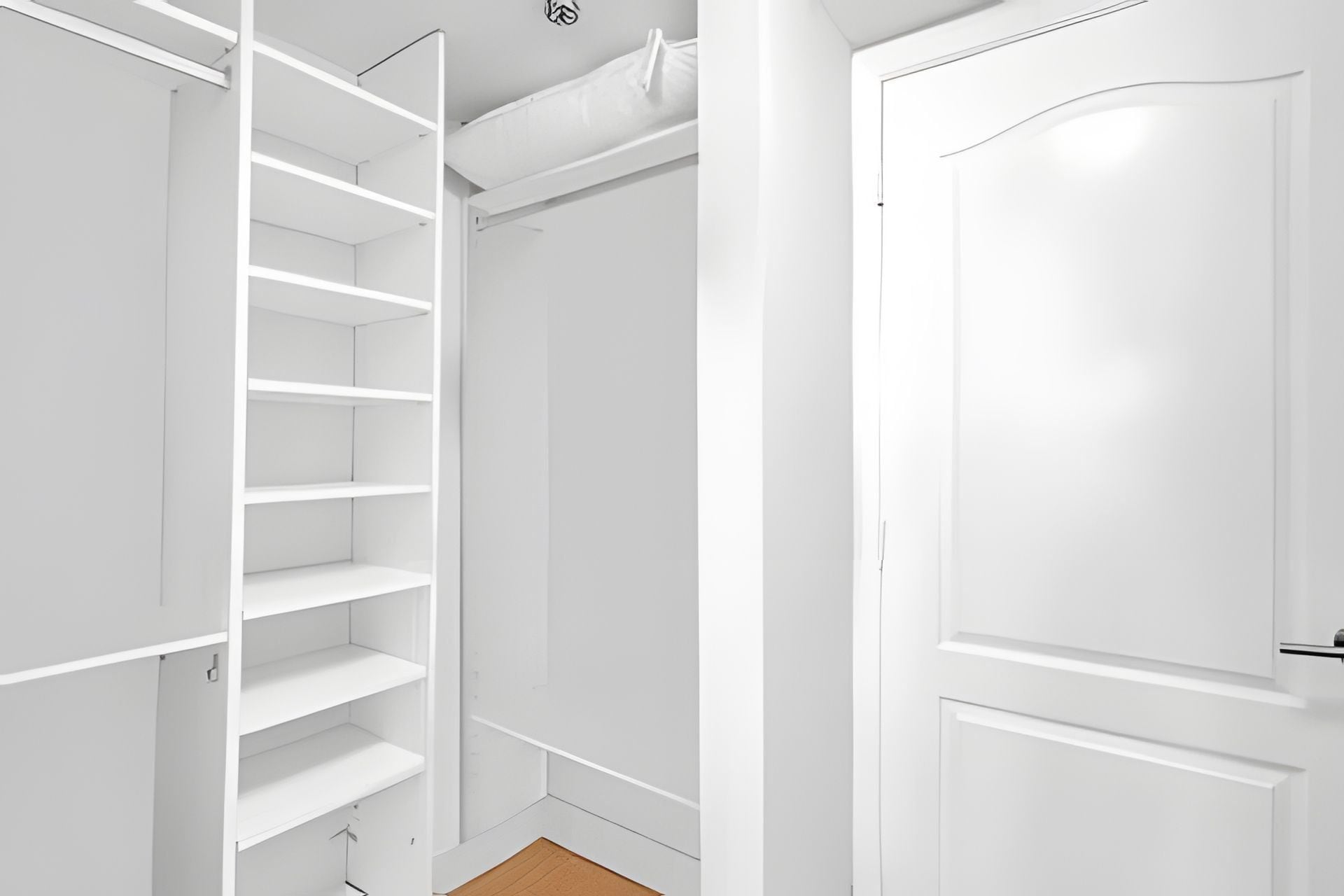 A white closet with multiple shelves and a door.