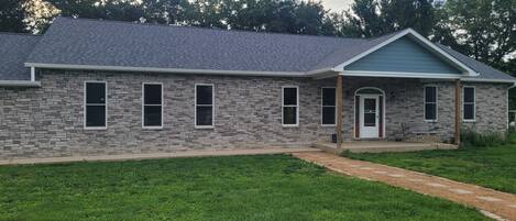 A single-story house with a stone facade, a front porch, and a covered entryway.