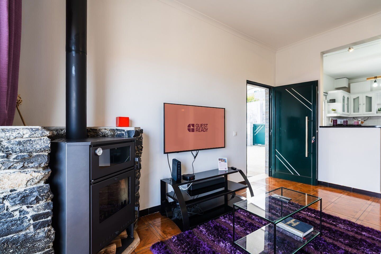 A modern living room with a stone fireplace, a flat-screen TV, and a glass coffee table.