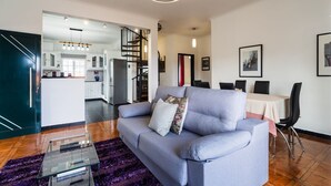 Een moderne woonkamer met een bank, een glazen salontafel en een eethoek met stoelen en een tafel.