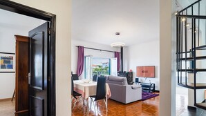 Een moderne woonkamer met een bank, eettafel, stoelen, een televisie en een balkon met uitzicht.