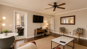 Una sala de estar con ventilador de techo, televisor de pantalla plana, mesa de comedor con sillas, sofá y mesa de centro.