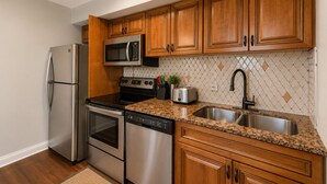 Una cocina con armarios de madera, electrodomésticos de acero inoxidable, encimera de granito y salpicadero decorado.