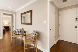 A hallway with two wicker chairs, a mirror, and a door. - Downtown Atlanta 1BR Condo on 24th Floor with Balcony, Walk to Stadium (Atlanta)