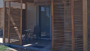 En lille træbygning med en overdækket terrasse, en dør og et vindue.