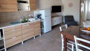 Et moderne køkken med træskabe, en hvid bordplade, indbygget ovn og et spiseområde med bord og stole.