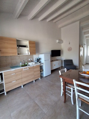 Une cuisine moderne avec des meubles en bois, un plan de travail blanc, un four encastré et un coin repas comprenant une table et des chaises.