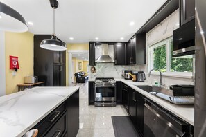 Una cocina moderna con armarios oscuros, una estufa de acero inoxidable y una encimera de mármol.