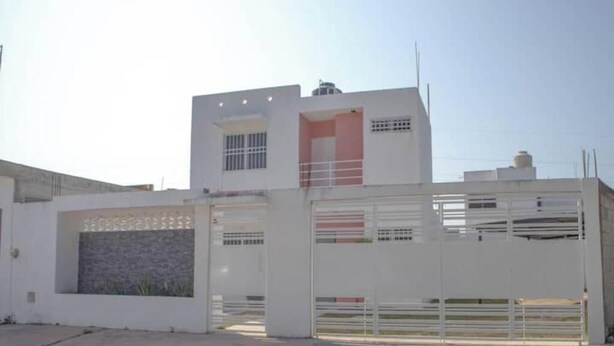 A modern two-story house with a gated entrance, a small balcony, and a visible chimney. - The House in the Southeast / Covered Parking / Family Home (Chetumal)