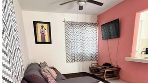 A room with a bed, a blue hammock chair, a ceiling fan, a TV, and a patterned wall. - The House in the Southeast / Covered Parking / Family Home (Chetumal)