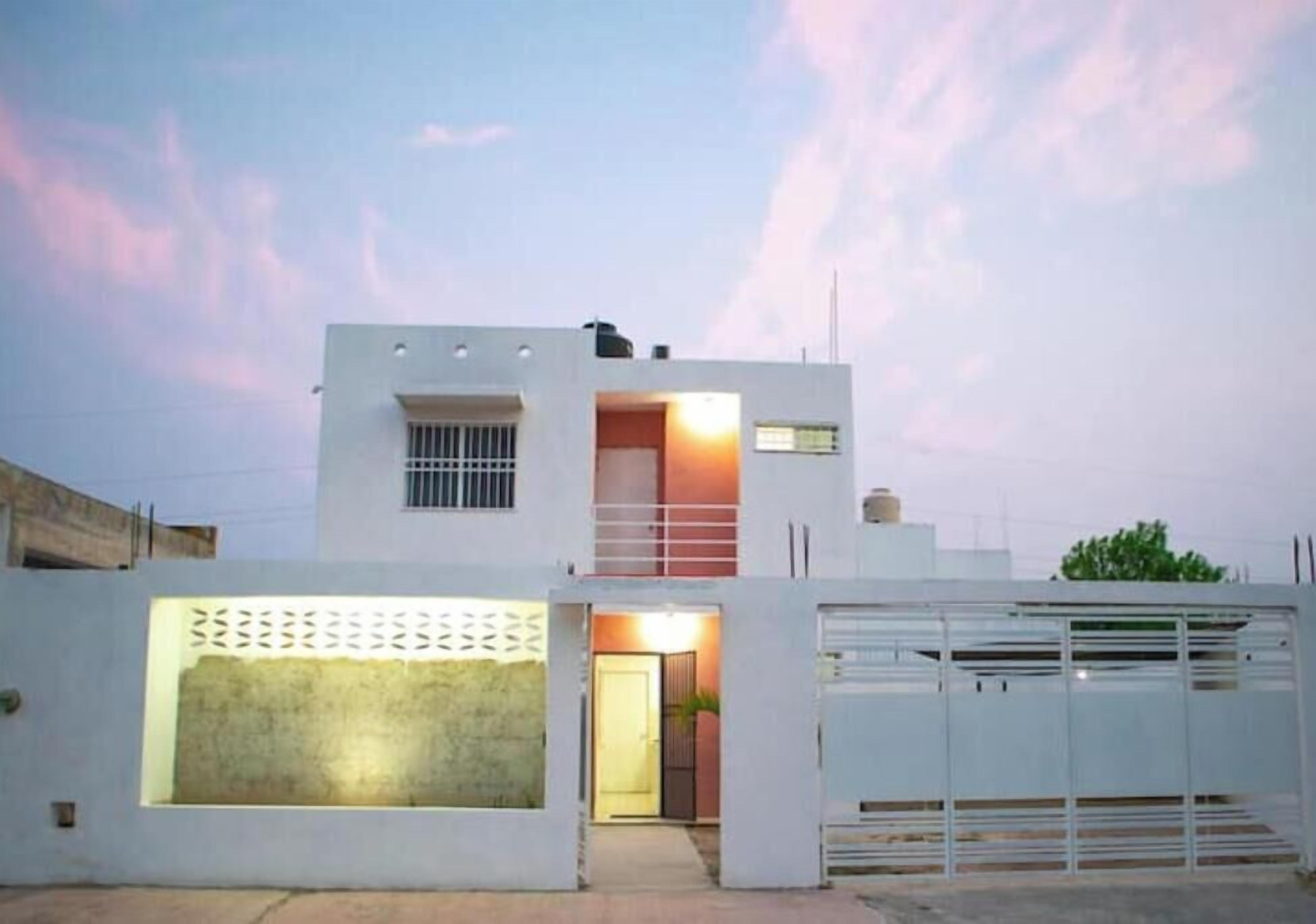 Una casa moderna de dos pisos con garaje, un pequeño balcón y entrada con portón.
