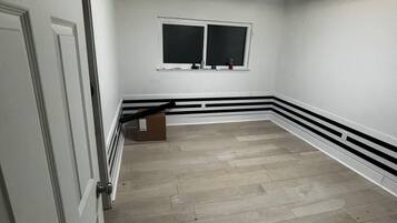 A room with a white door, a window, and a ceiling light.