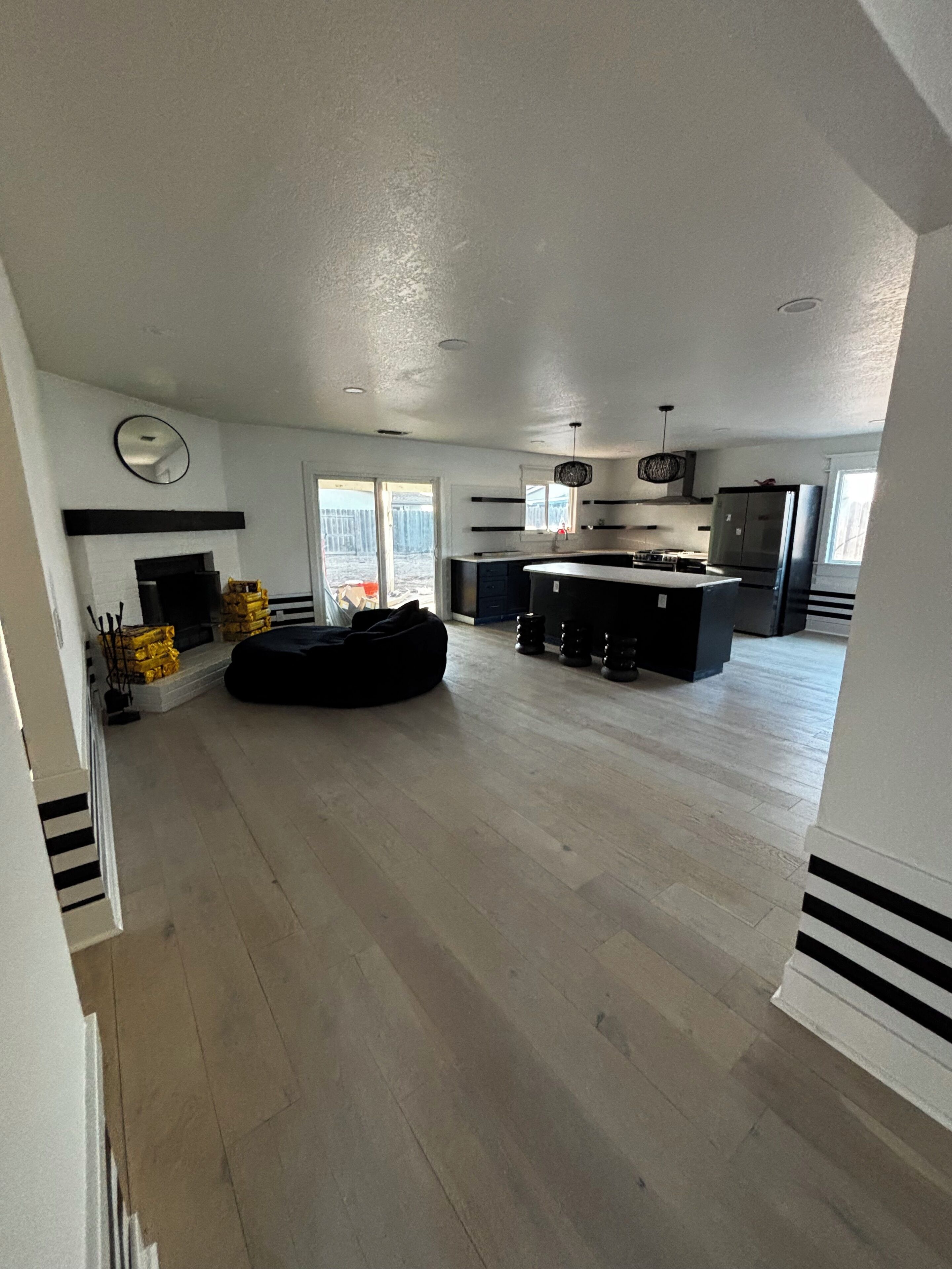 A spacious living area with a fireplace, a large black bean bag, and a kitchen with a refrigerator and stove.. Peaceful four bedroom home