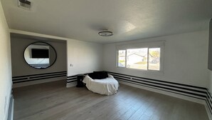 A room with a large window, a round mirror, and a bed. - Peaceful four bedroom home (Ripon)