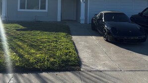 A residential house with a garage, a driveway, and two parked cars. - Peaceful four bedroom home (Ripon)