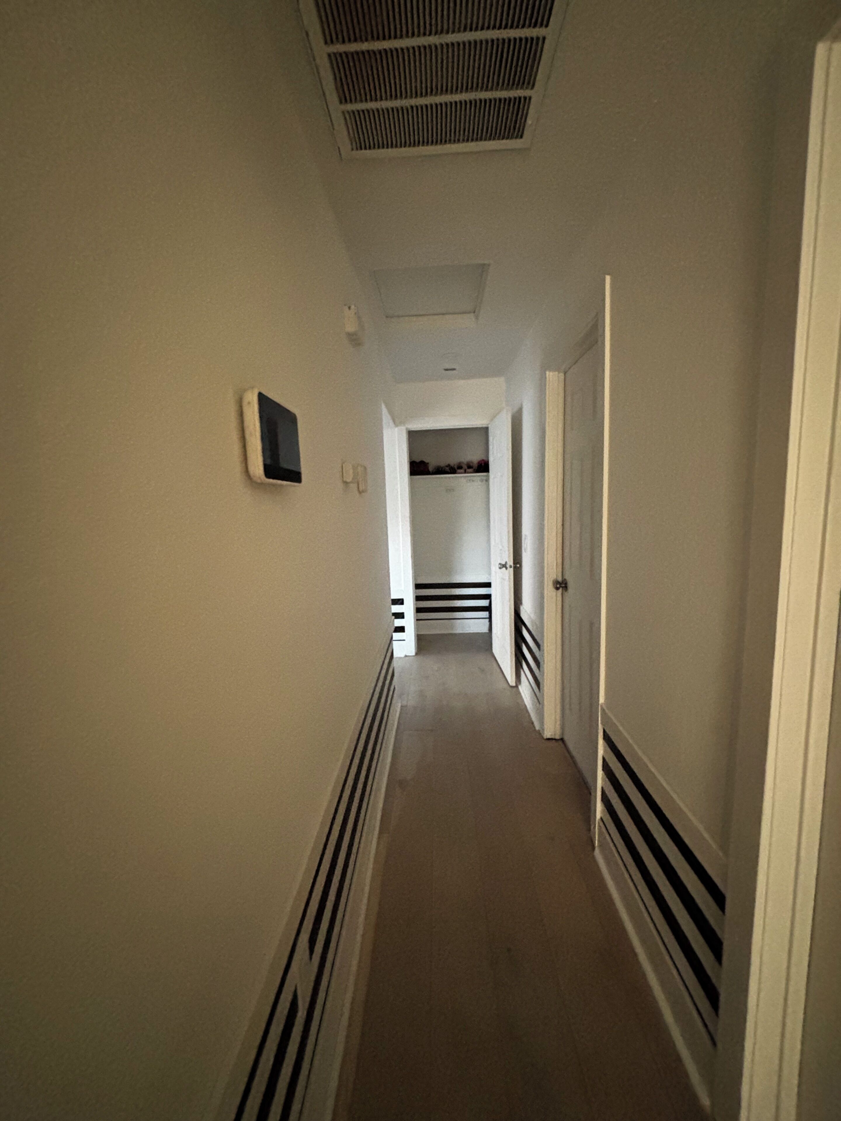 En smal hall med en ventil i taket, en dörr på höger sida och en dörr längst fram.