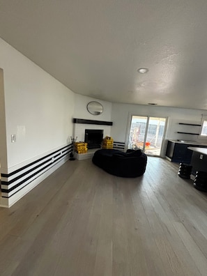 Un espacio habitable amplio con chimenea, zócalo a rayas negras y blancas y un sillón de tiro negro.