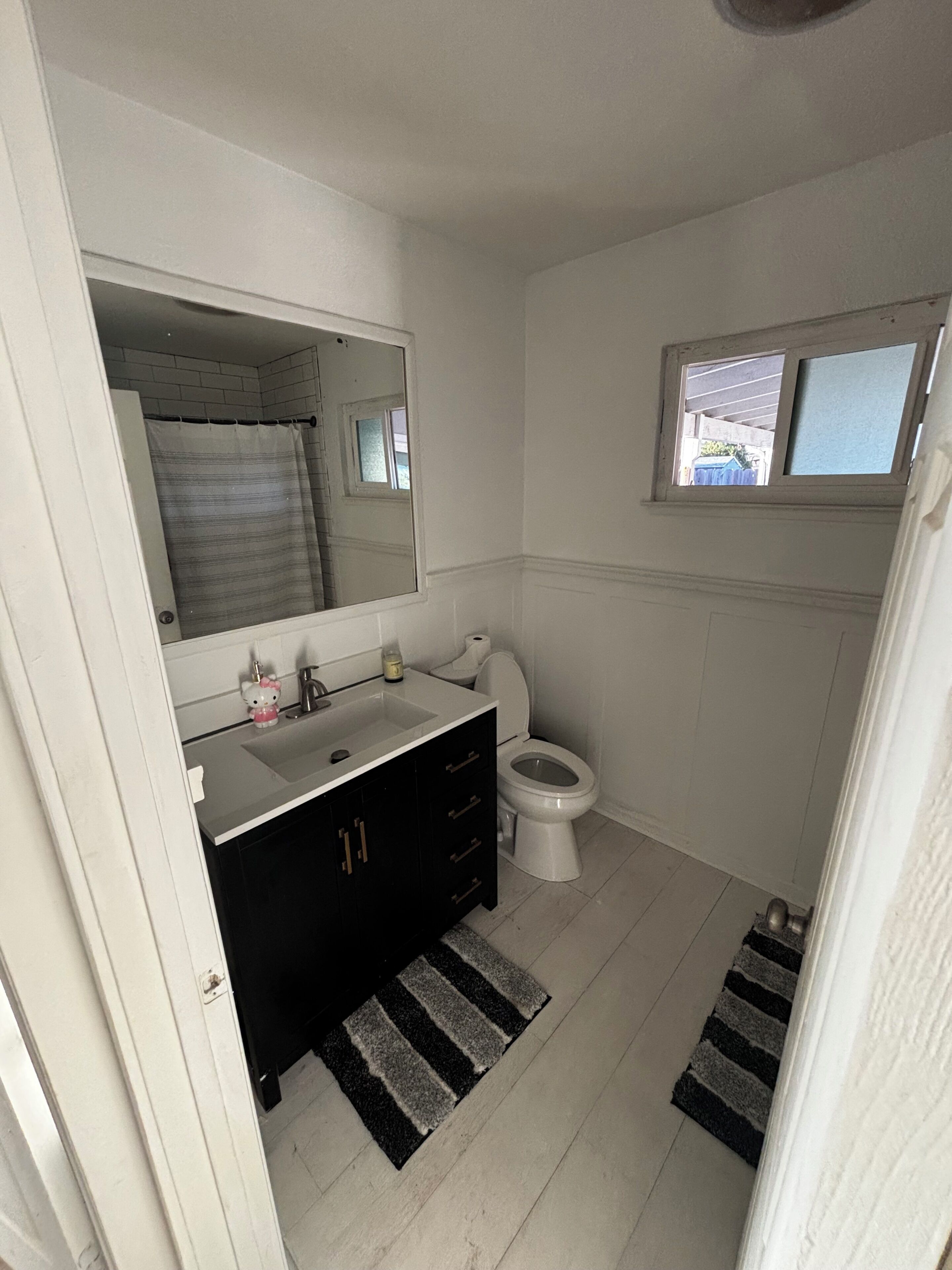 Ein Badezimmer mit Waschbecken, Spiegel, Toilette und einem kleinen Fenster.