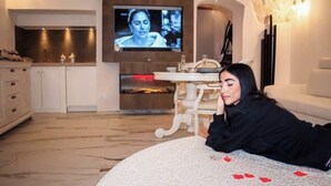 Ein Zimmer mit Fernseher, Kamin, Esstisch und einer Couch.