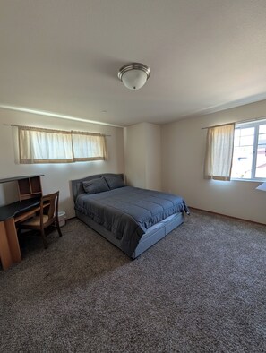 A bedroom with a bed, a desk, and two windows with curtains. - Centrally located, 3-bedroom condo in beautiful Bellingham, great location! (Bellingham)
