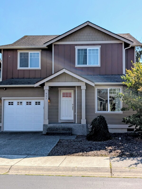 A two-story house with a garage, a front door, and a small porch.