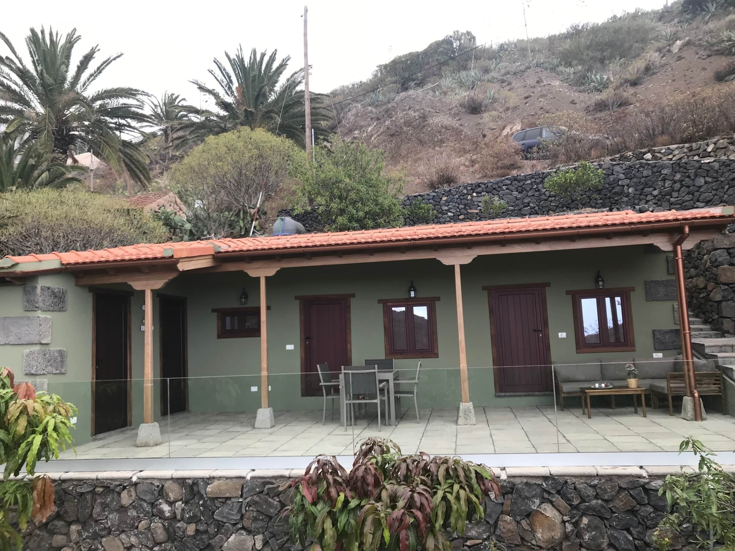 A house with a stone wall, a tiled patio, and a small table.