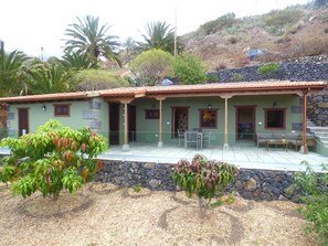 A building with a tiled patio, stone walls, and a green roof. - El pirguan, holiday house (Vallehermoso)