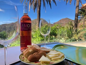 A table with a bottle of rosé wine, two glasses, bread, and cheese. - El pirguan, holiday house (Vallehermoso)