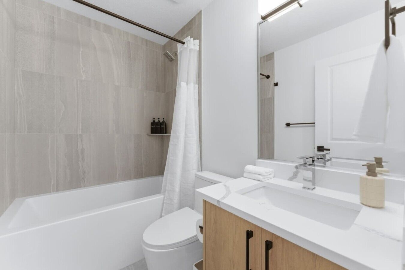 A modern bathroom with a bathtub, toilet, and vanity.