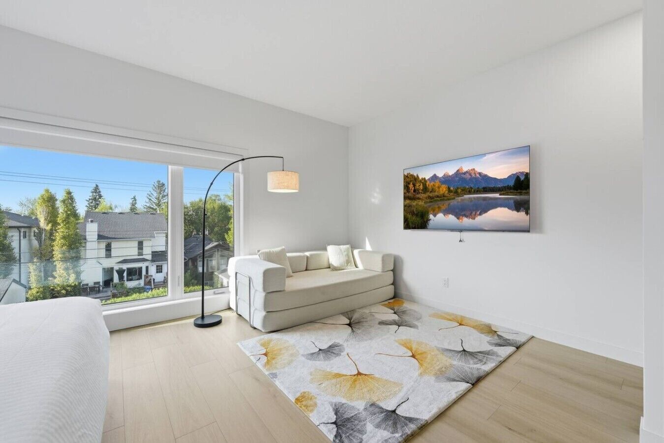 A modern living room with a sofa, a floor lamp, a large window, and a painting on the wall.