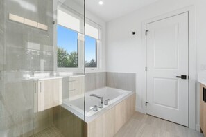 Un bagno moderno con box doccia in vetro, una vasca da bagno freestanding e una porta bianca.