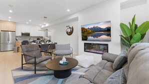 A modern living room with a sofa, chairs, a coffee table, a fireplace, and a kitchen in the background. - 4 Ensuites | Private Rooftop | Bar Lounge | Slps 8 (Calgary)