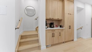 A modern kitchen with wooden cabinets, a countertop, and a coffee maker. - 4 Ensuites | Private Rooftop | Bar Lounge | Slps 8 (Calgary)