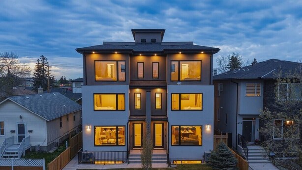 A multi-story residential building with multiple windows, a front entrance, and a visible staircase. - 4 Ensuites | Private Rooftop | Bar Lounge | Slps 8 (Calgary)