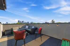 En tagterrasse med loungesæt, to stole og et lille bord.