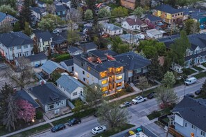 Un quartier résidentiel avec des maisons modernes, un immeuble à deux étages doté de balcons et une rue où sont garées des voitures.